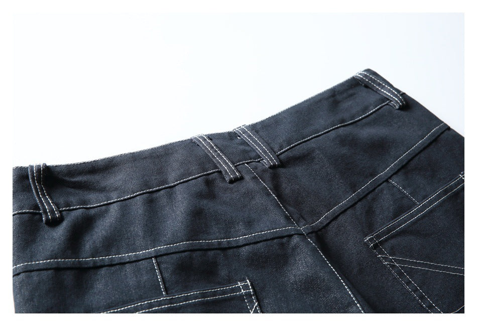 Close-up of dark denim trousers showing the waistband, belt loops and upper back pockets.