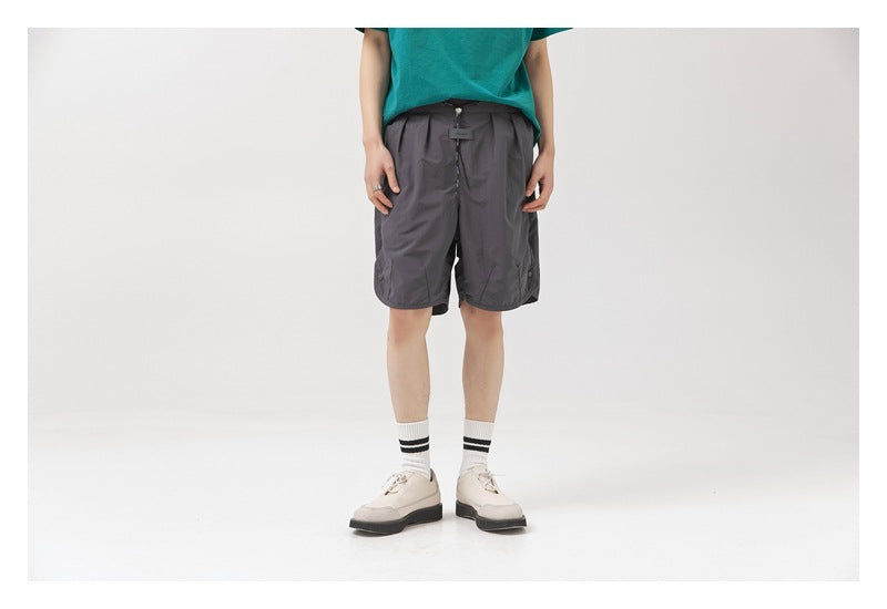 Front view of a model wearing charcoal gray shorts with a drawstring waist and side pockets.