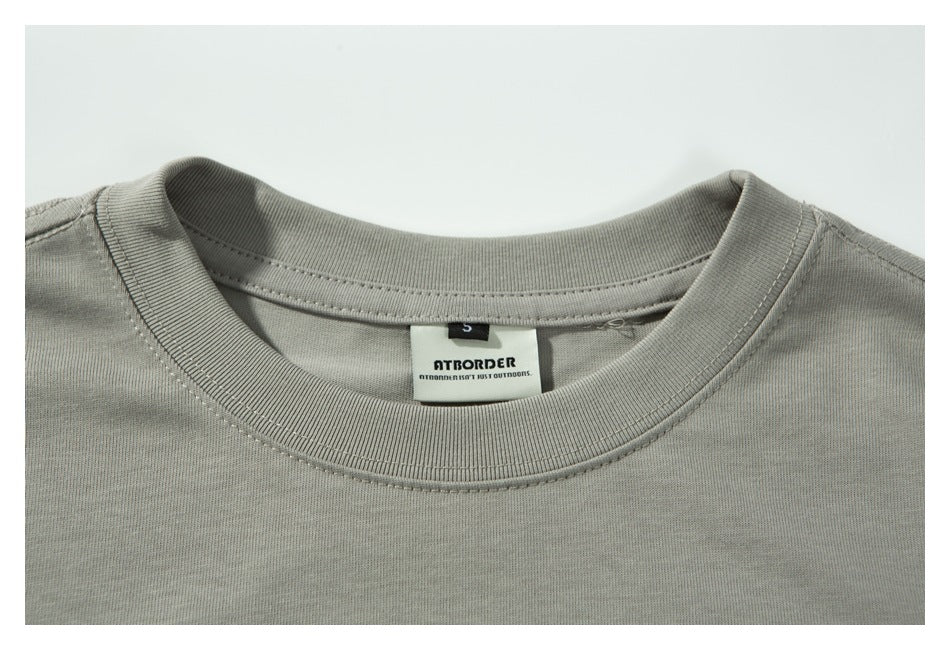 Close-up of the light gray shirt's ribbed crew neck and sewn-in brand label.