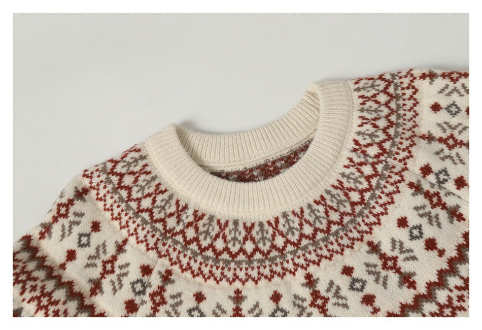 Close-up of an ivory sweater's ribbed crew neck and red and taupe patterned yoke.