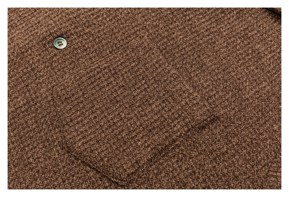 Close-up of brown knit fabric with a single button, showing the textured stitch.
