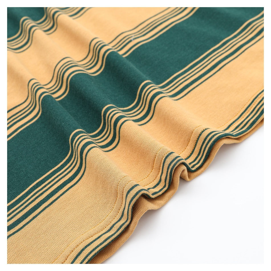 Close-up of a mustard and dark green striped garment hem with visible stitching.