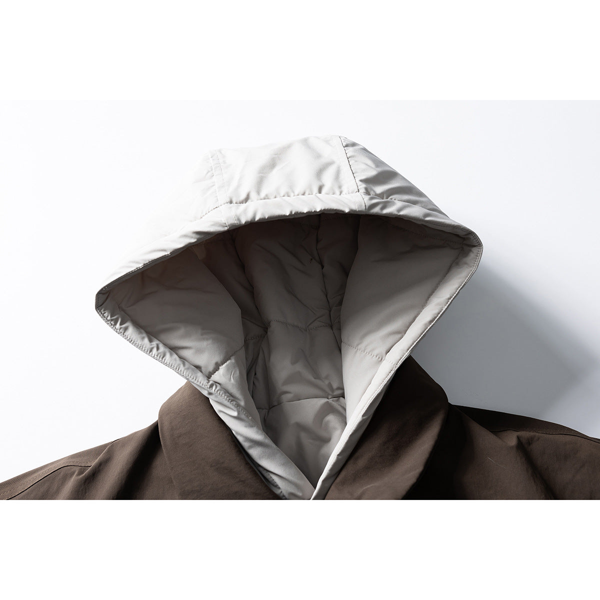 Close-up of a light gray padded hood attached to a dark brown jacket.