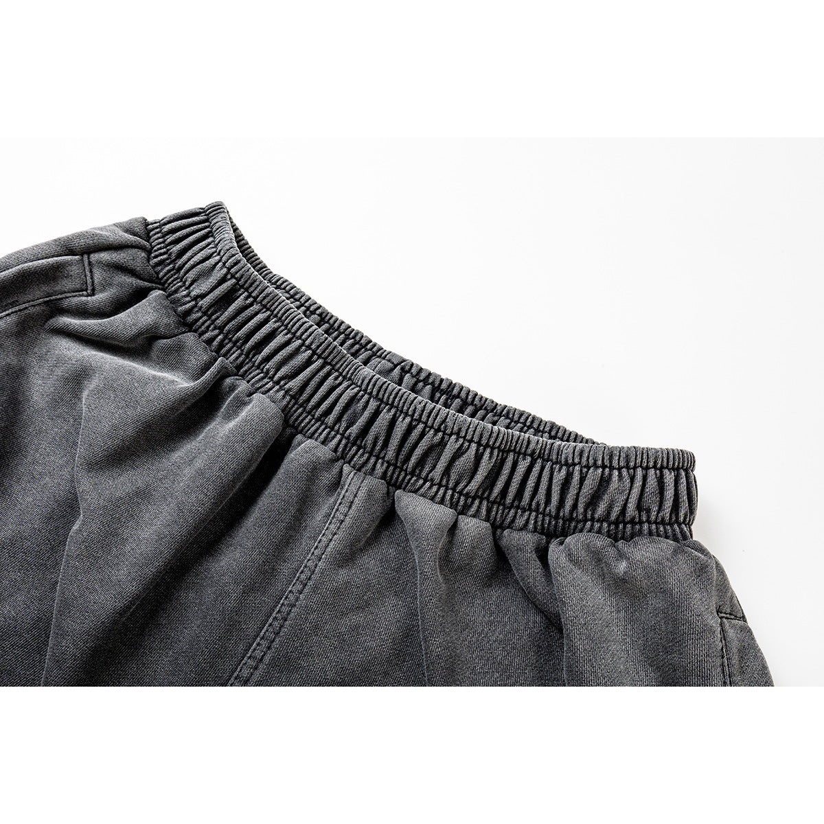 Close-up of charcoal-gray pants showing the gathered elastic waistband and upper fabric.