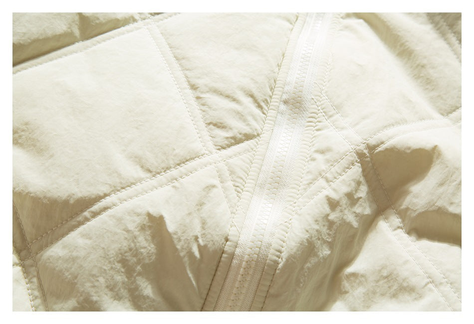 Close-up of an ivory quilted jacket with a central zipper and intersecting stitched panels.