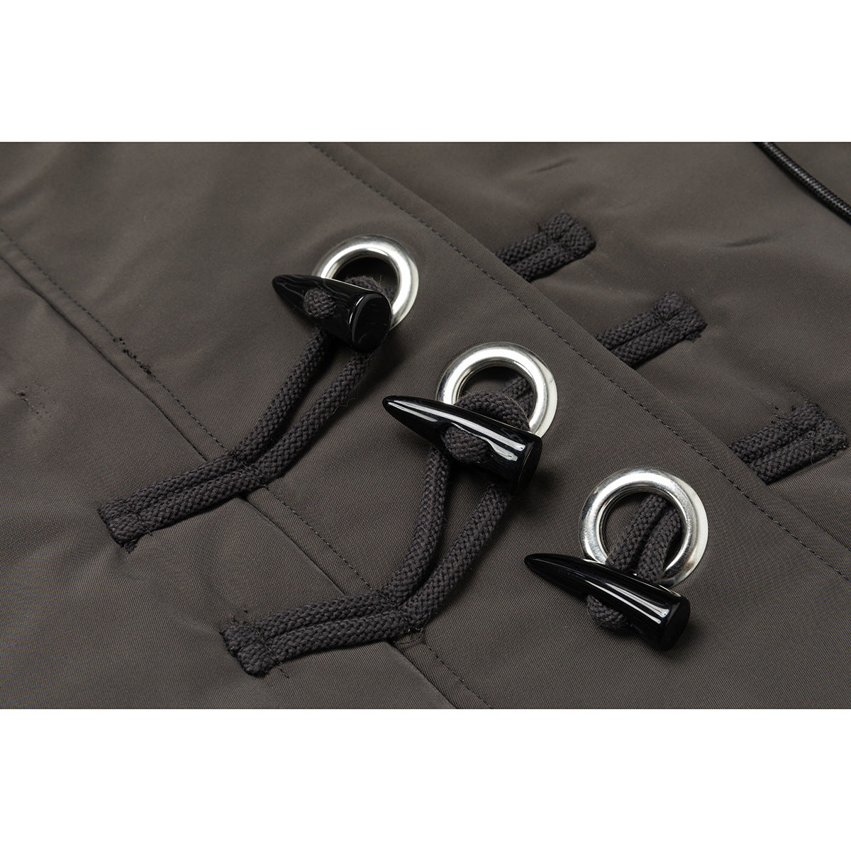 Close-up of three black cord toggle closures threaded through silver rings on the jacket.