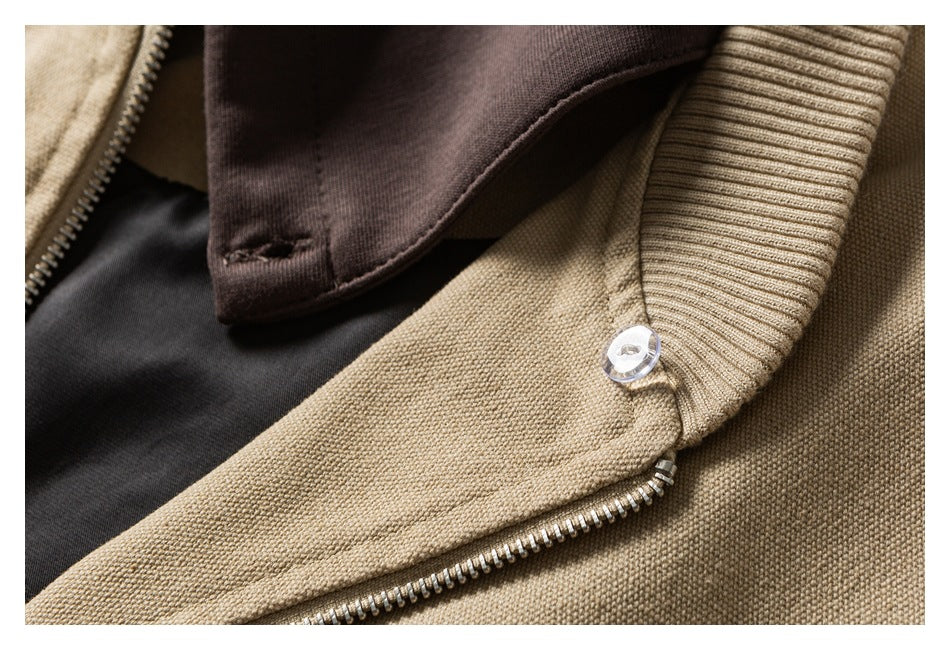 Close-up of the beige jacket's metal zipper, ribbed collar edge, and dark brown hood.