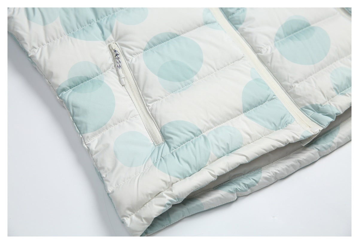 Lower front of a white and pale aqua circle-print puffer jacket, showing a zip pocket and hem.