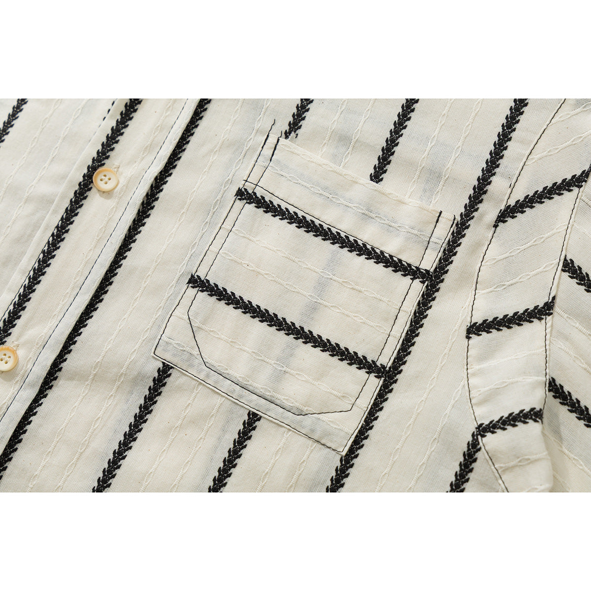 Close-up of a chest pocket on a cream shirt with black braided stripes and cream buttons.