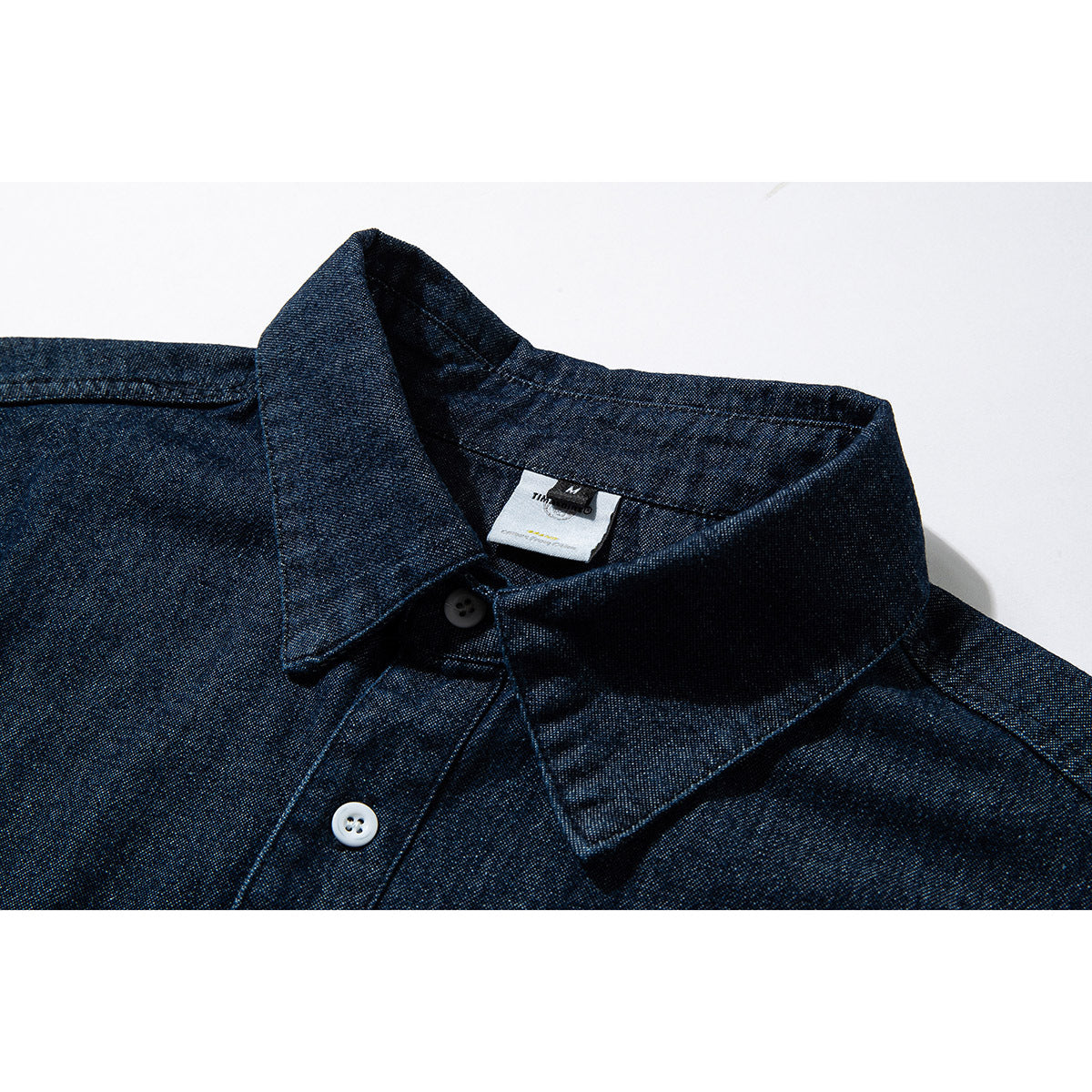 Close-up of a dark indigo button-up shirt collar, placket, and sewn-in neck label.