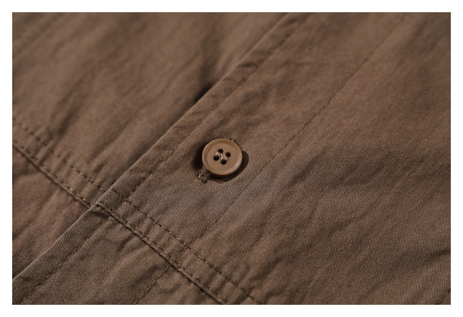 Close-up of a brown shirt with a four-hole button and intersecting stitched seams.