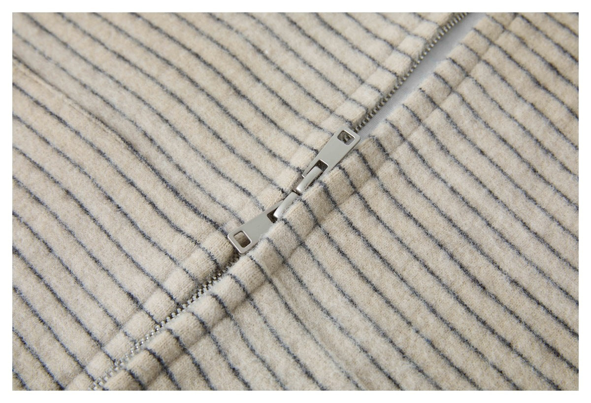 Close-up of a silver zipper on cream fabric with thin dark stripes.
