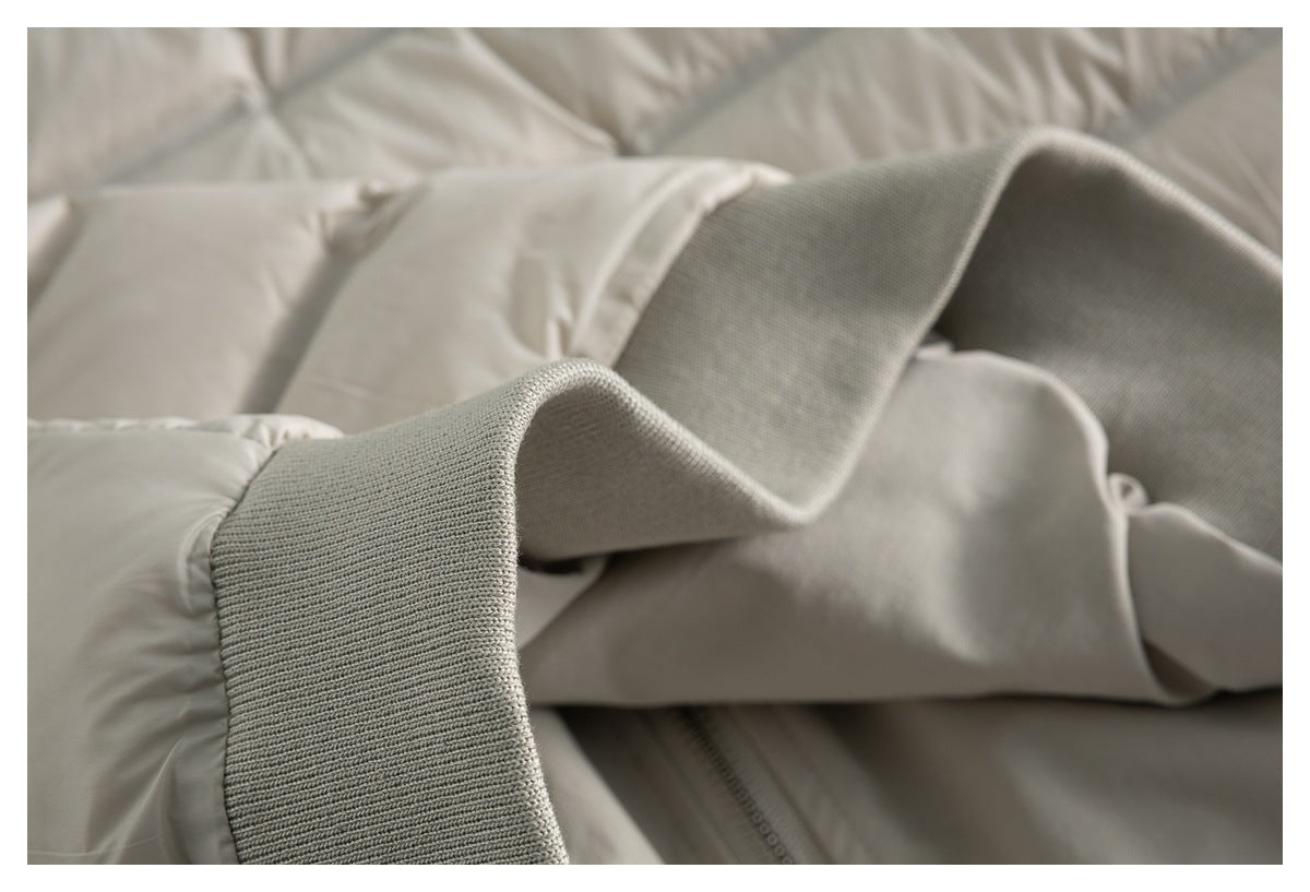 Close-up of a light beige jacket with a wide rib-knit cuff beside the padded sleeve.