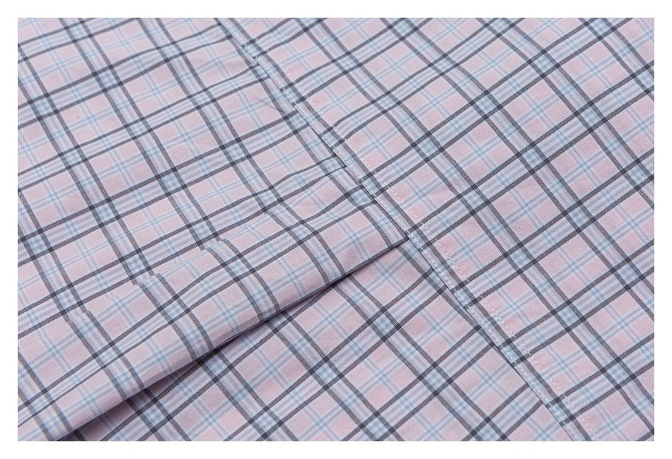 Close-up of the stitched front placket on a pale pink plaid shirt.