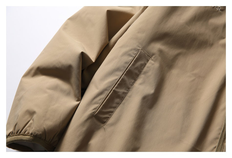 Close-up of a tan jacket sleeve with an elastic cuff and a slanted welt pocket.