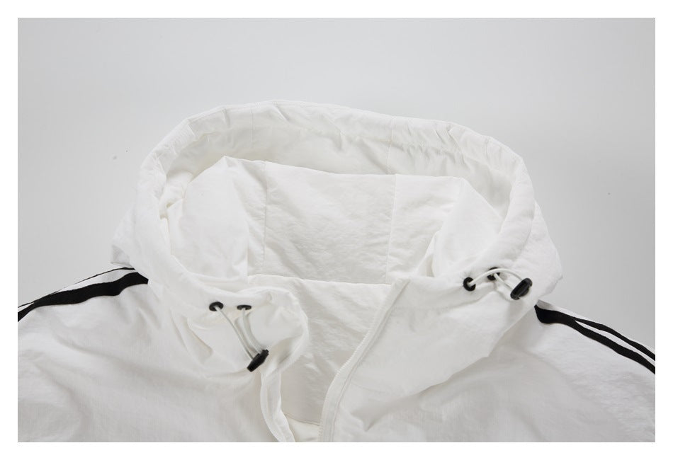 Close-up of a white jacket's open hood and front zipper, with black shoulder stripes and drawcords.
