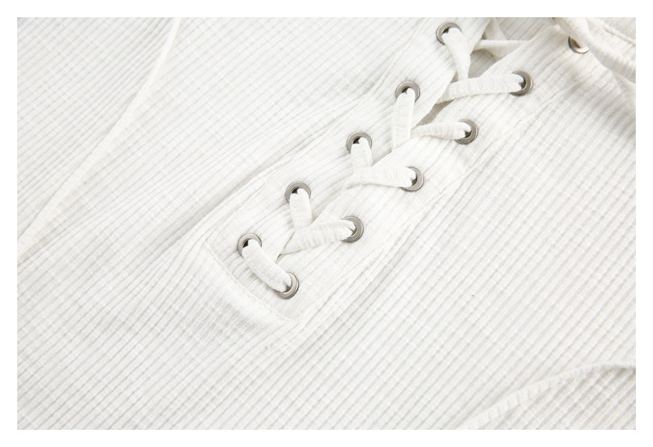 Close-up of the off-white top's lace-up front, with fabric ties threaded through metal eyelets.