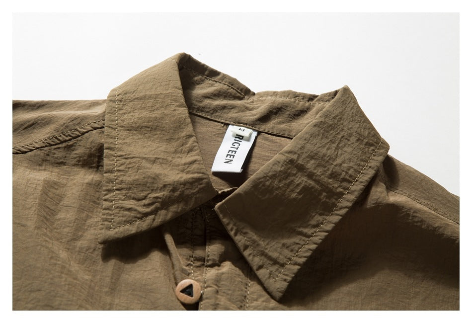 Close-up of an olive-brown shirt collar, button, stitching, and sewn-in neck label.