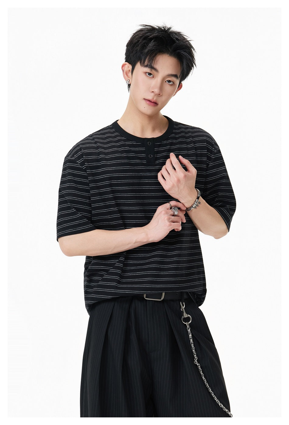Close view of a model wearing a black short-sleeve shirt with thin horizontal stripes and a two-button placket.