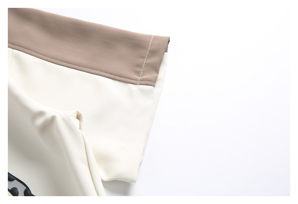 Close-up of the taupe sleeve trim and ivory shirt fabric.