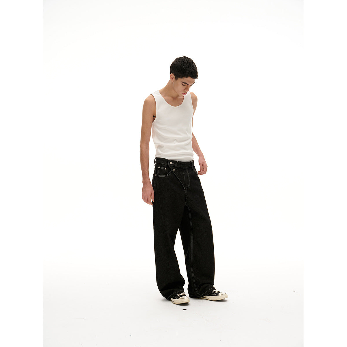 Model in a white tank and loose black jeans, shown full-length at a slight angle looking down.