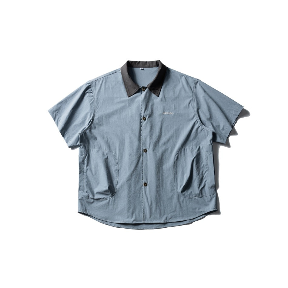 Blue short-sleeve button-up shirt with dark gray collar and two curved side pockets, flat lay front view