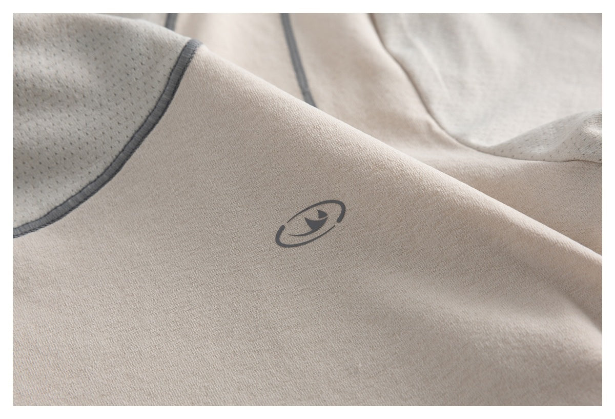 Close-up of a beige garment with a small dark emblem and gray-edged perforated mesh panel.