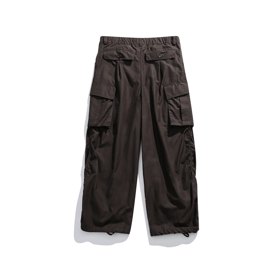 Back view of dark charcoal cargo pants with two button-flap rear pockets, large side pockets, and gathered hems.