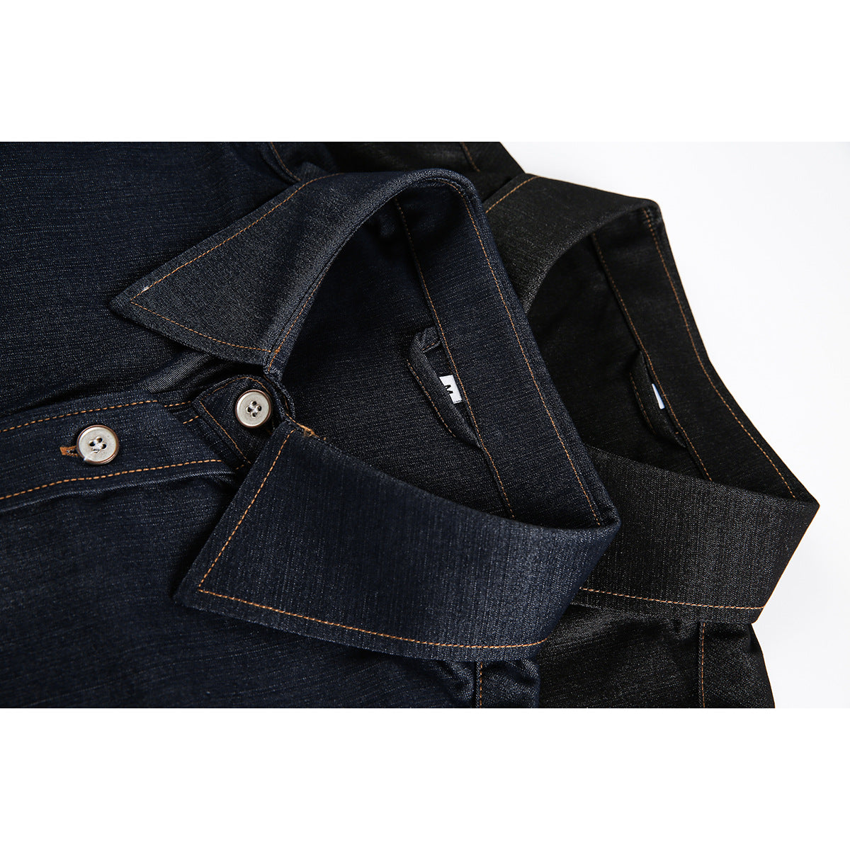 Close-up of dark indigo and black denim shirt collars with orange contrast stitching and buttoned plackets.