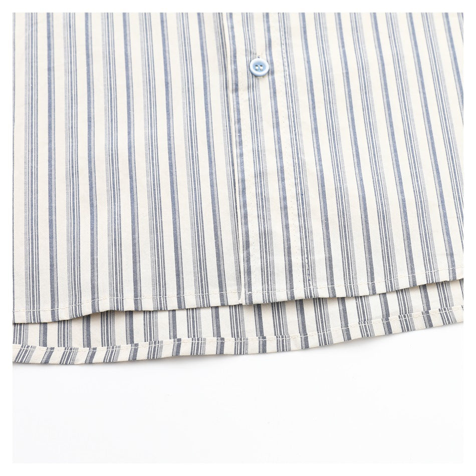 Close-up of the striped shirt's lower hem and a pale blue button on cream fabric.