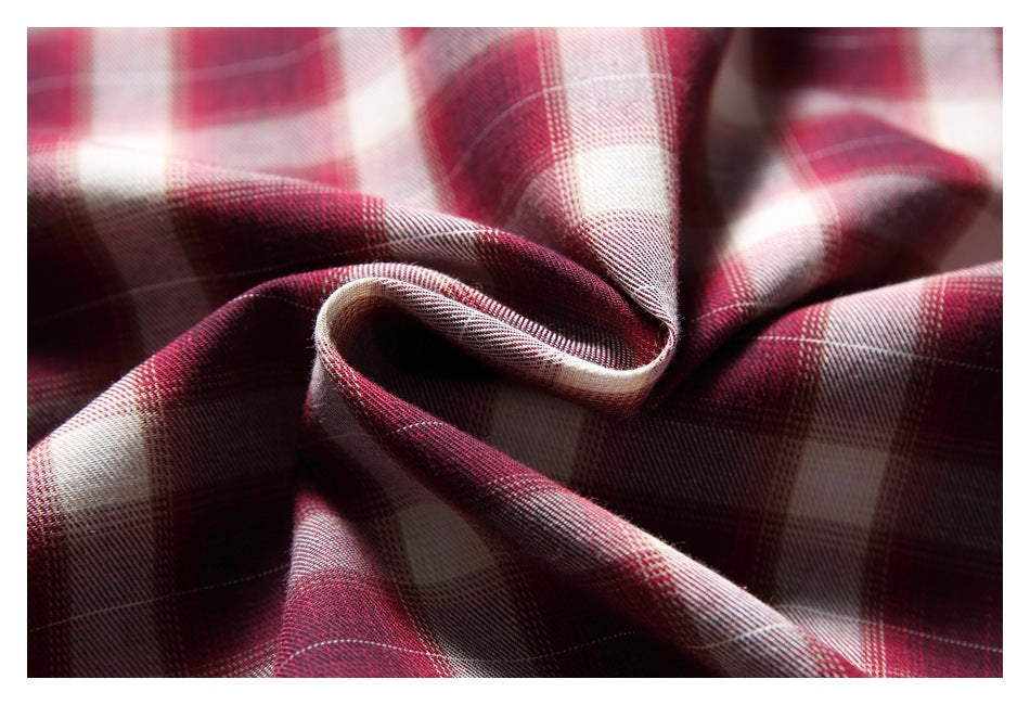 Close-up of burgundy, cream, and gray plaid fabric gathered into soft folds.