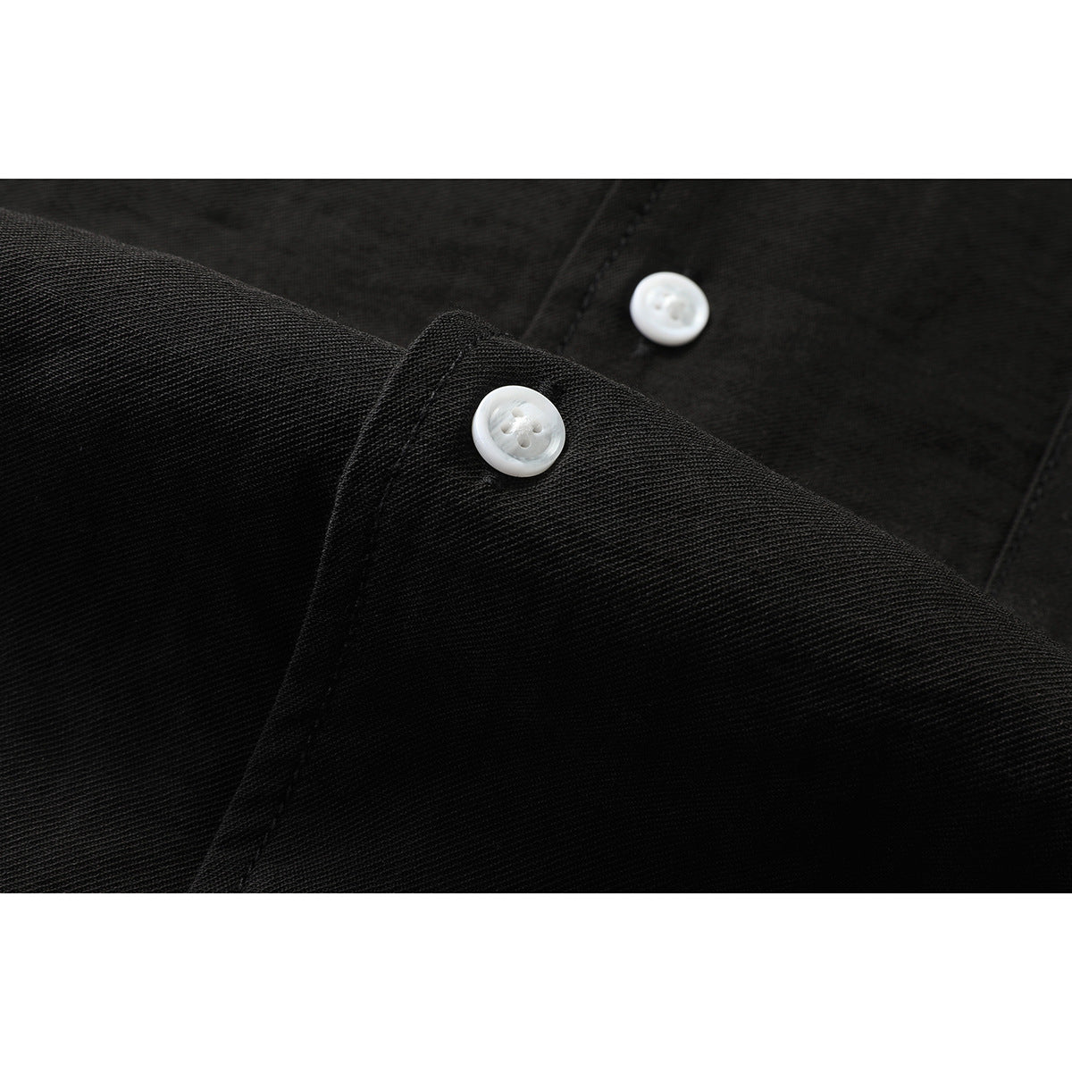Close-up of two white buttons on black shirt fabric, showing the stitching and texture.