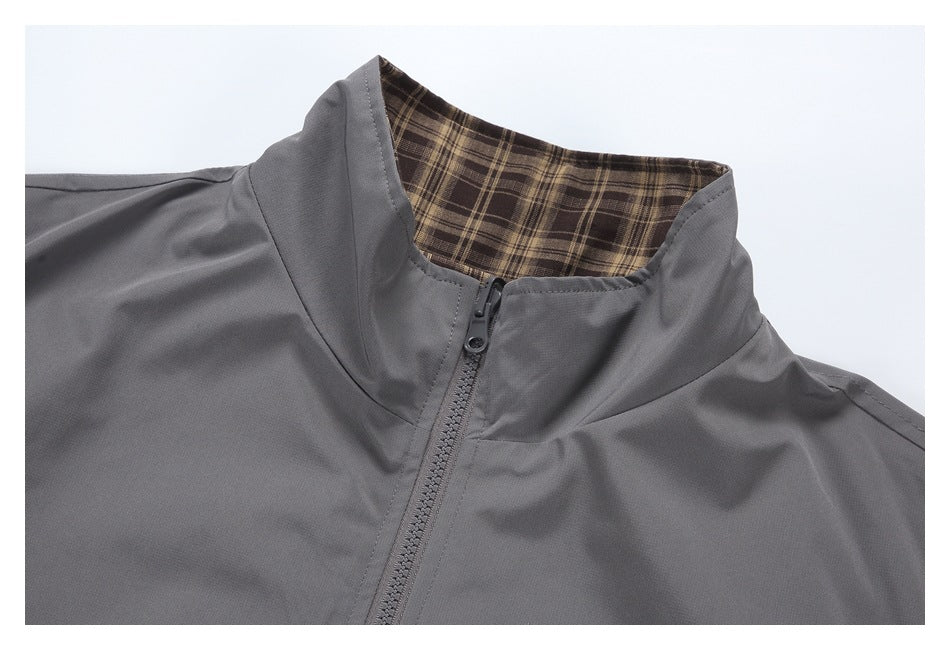 Close-up of a gray zip-front jacket collar with brown plaid lining.