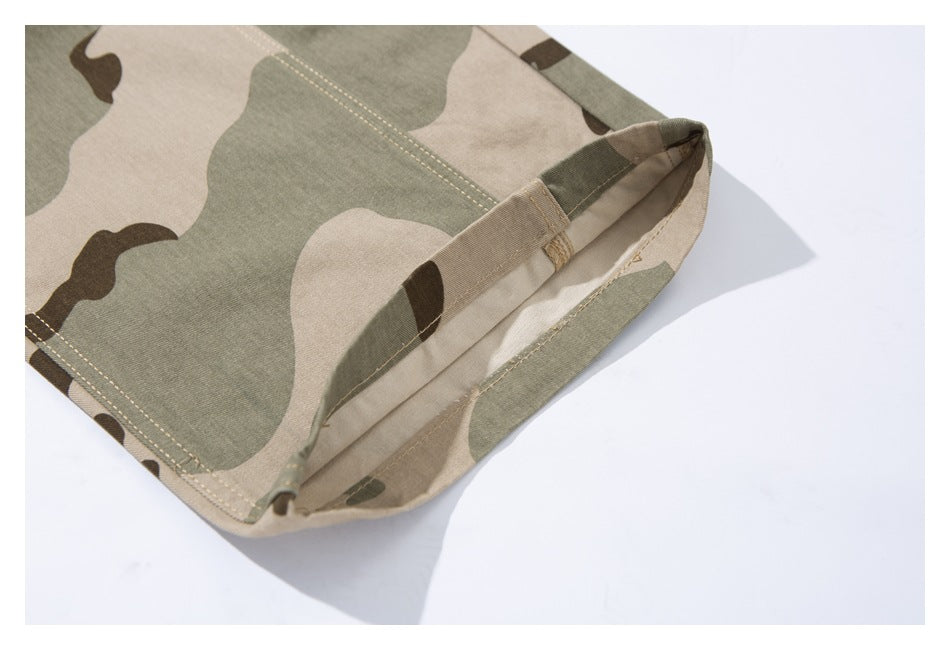 Close-up of a beige, olive, and brown camouflage garment edge with folded seam and visible stitching.