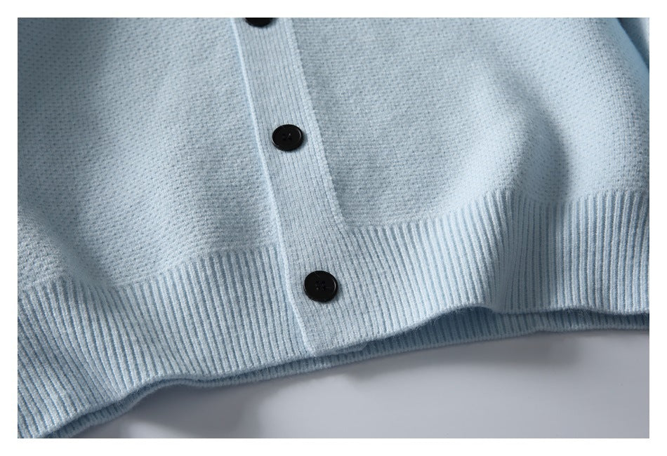 Close-up of the pale blue cardigan's black buttons, textured knit, and ribbed hem.