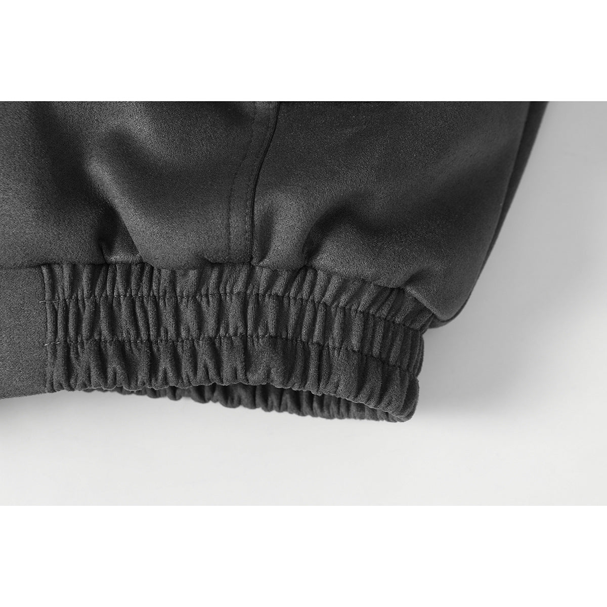 Close-up of the charcoal jacket's gathered elastic hem and stitched seam.