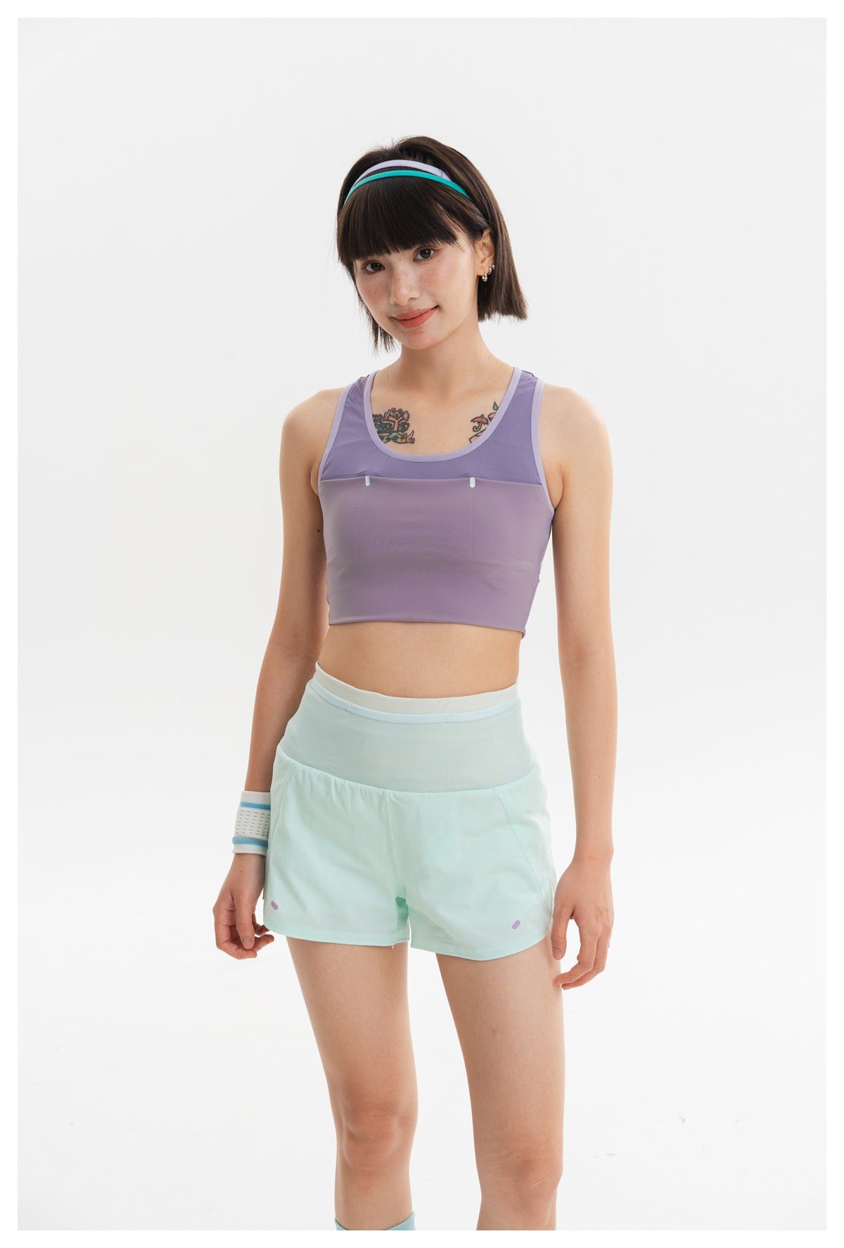 Front view of a model wearing a lavender cropped athletic tank with mesh panels and pale mint shorts.