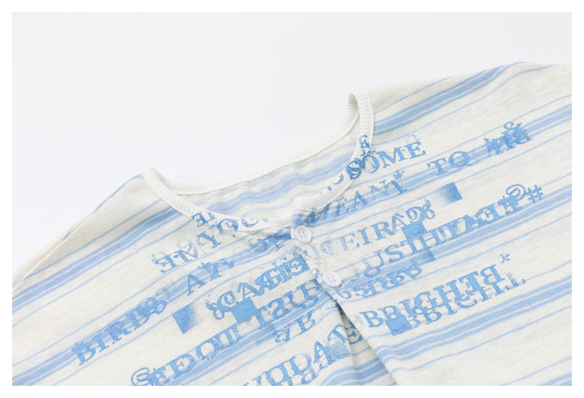 Close-up of the cream and blue striped top's printed front, ribbed crew neck, and two-button placket.