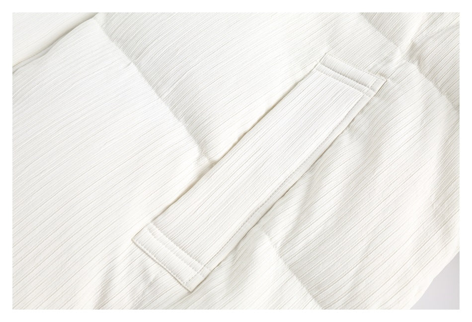 Close-up of an ivory ribbed garment with a wide stitched band or cuff.