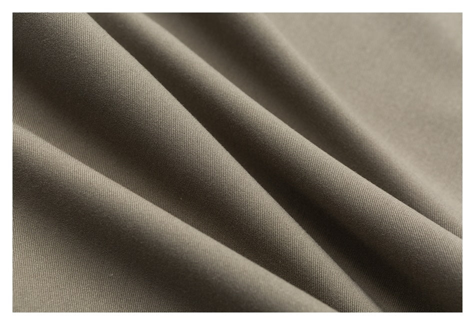 Extreme close-up of taupe trouser fabric arranged in soft folds.