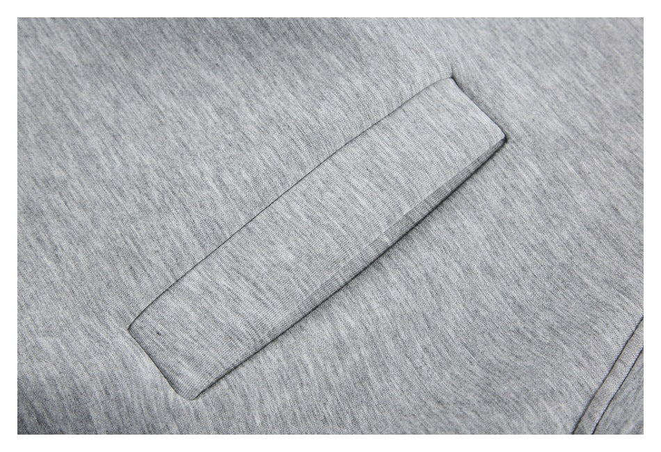 Close-up of a rectangular welt pocket on light gray heathered jacket fabric.
