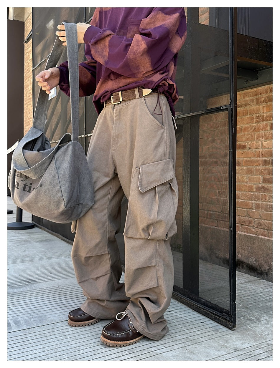 Model wearing loose taupe cargo pants with large flap pockets, shown with a purple patterned top.