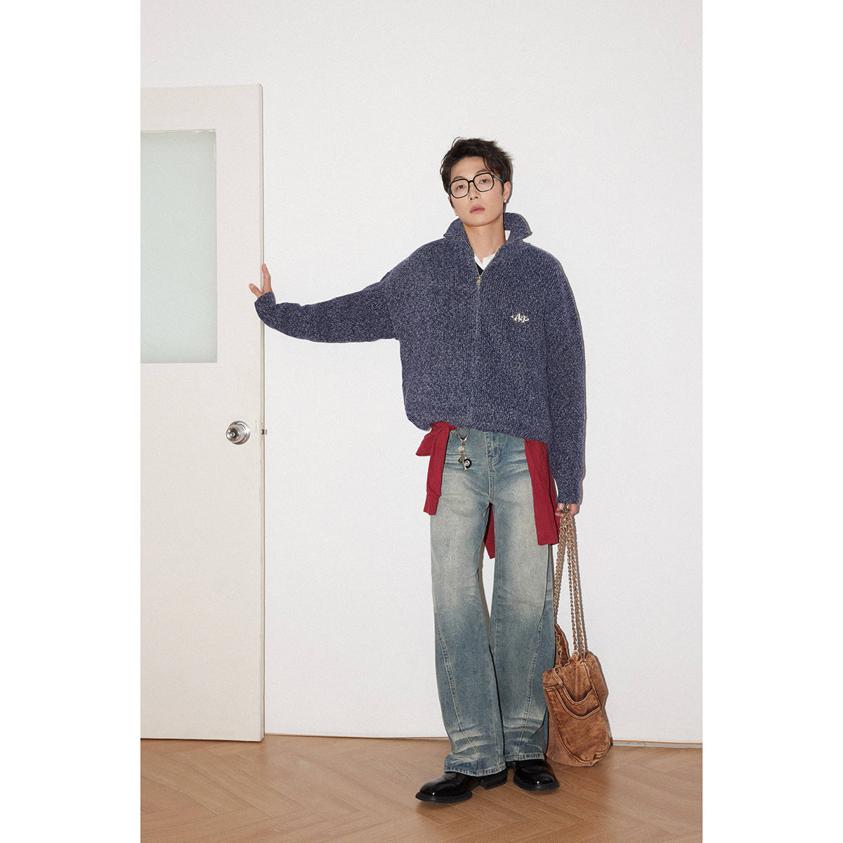 Model wearing an oversized navy ribbed zip-neck sweater with a raised collar and small chest emblem.