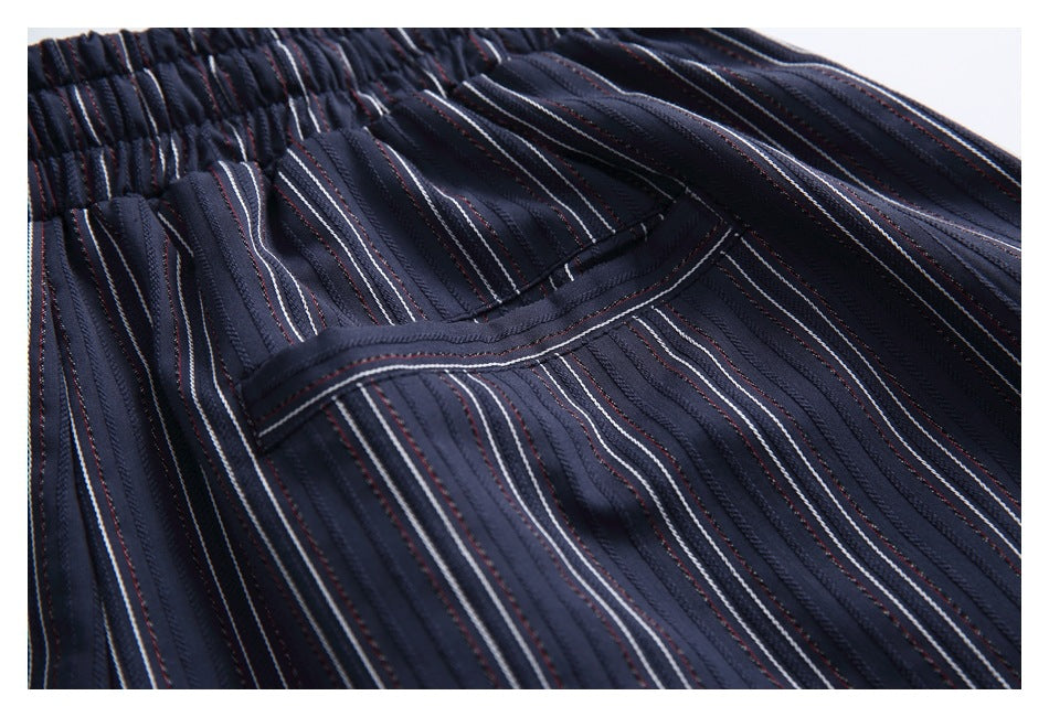 Close-up of a pocket and vertical white and muted red stripes on dark navy trousers.
