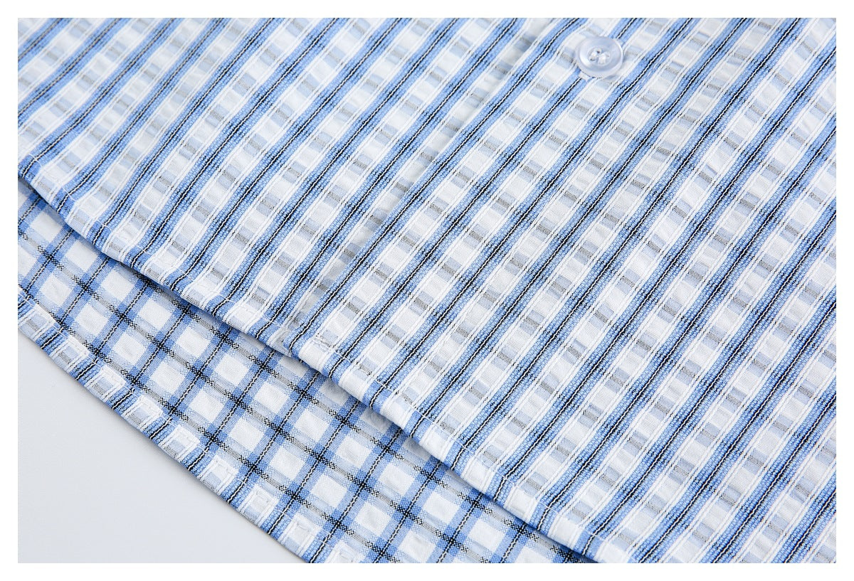 Close-up of blue-and-white striped shirt fabric, a white button, and a checked fabric edge.