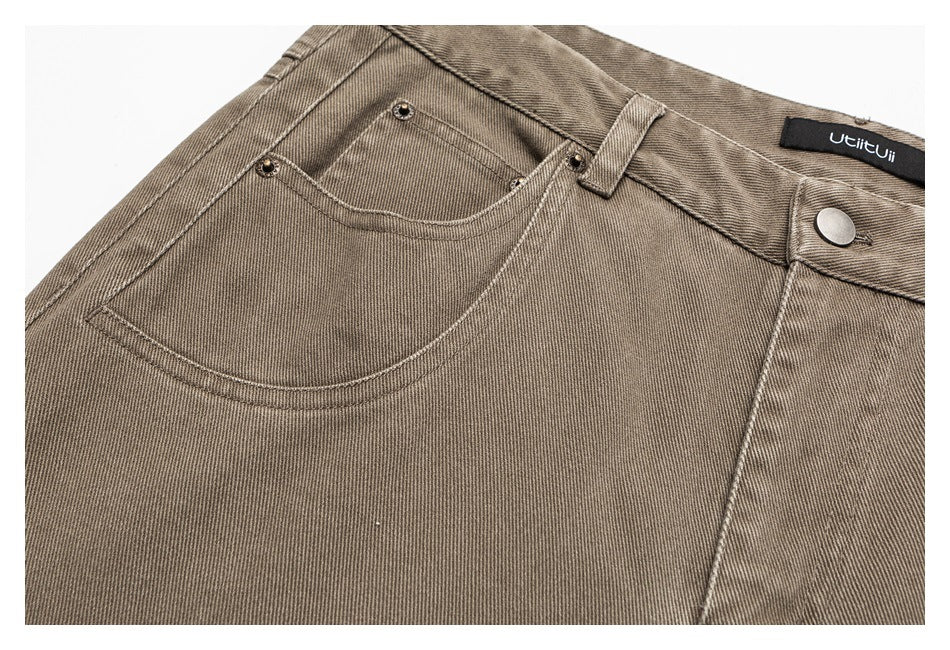 Close-up of taupe trousers showing the front pocket, small coin pocket, rivets, waistband and button.