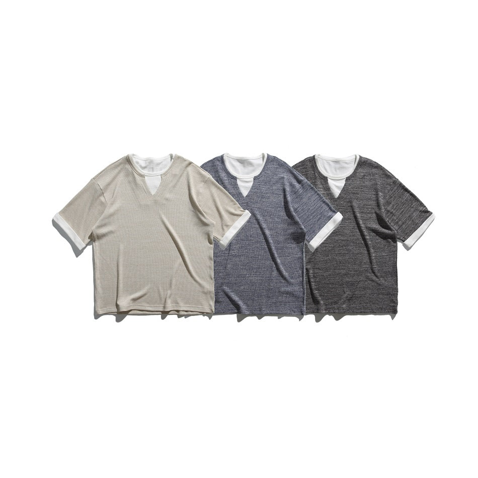 Three short-sleeve shirts with white neck and cuff trim in beige, blue-gray, and charcoal, shown from the front.