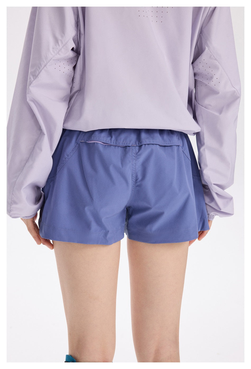 Rear view of a model wearing periwinkle-blue running shorts with a wide elastic waistband and back pocket.