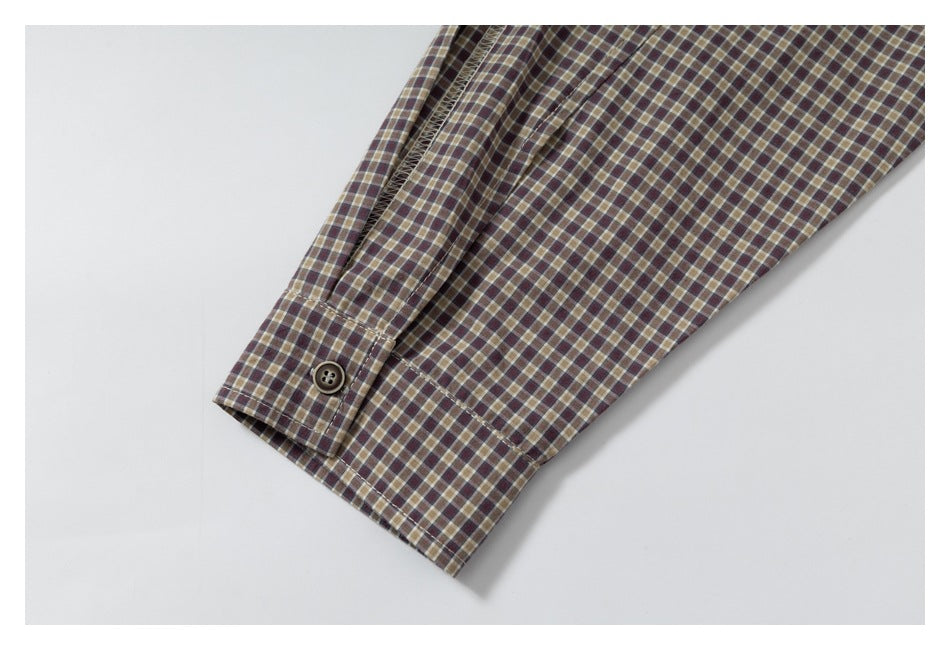 Close-up of a brown, burgundy, and tan plaid sleeve cuff with a dark button.