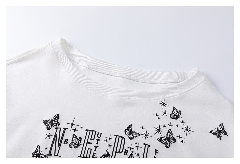 Close-up of a white sweatshirt neckline and black butterfly, star, and decorative lettering print.